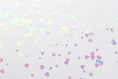 Holographic glitter confetti in heart shape on white background. Creative Valentine Day romantic composition flat lay top viewの写真素材