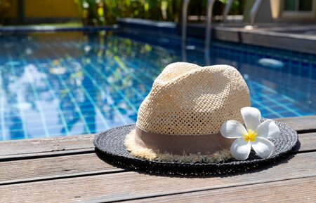 Straw hat and tropical flower near swimming poolの写真素材