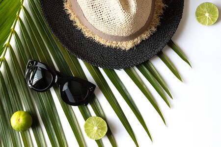 Summer composition with fruits, hat and tropical palm leaf on white background. Travel concept flat lay, top view, copy spaceの写真素材