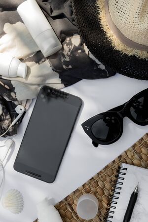 Trendy sunglasses, planner, hat and cosmetic cream with palm leaf shadow on white background. Beach travel blog templateの写真素材