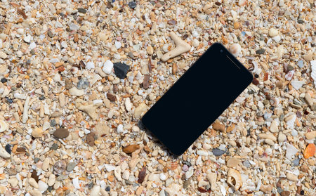 Smart phone  with empty screen on tropical sand beach background. Technology business and travel concept.の写真素材