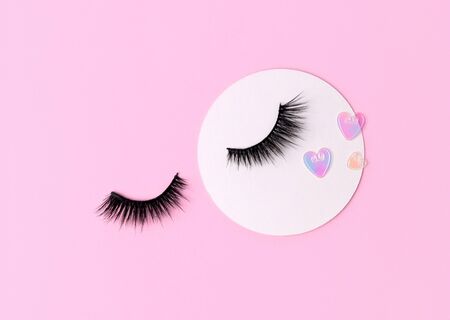Creative layout with eyelashes. Closed eyes on pastel pink backgroundの写真素材