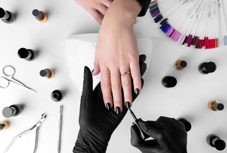 Woman making manicure in beauty salon. Professional tools and nail polish on white table. Hands care conceptの写真素材