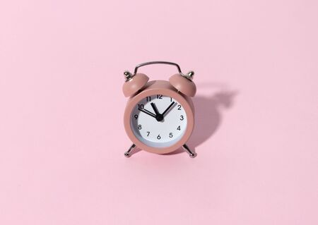 Pink alarm clock on pastel color paper background with copy space. Creative morning time minimal style concept template.の写真素材