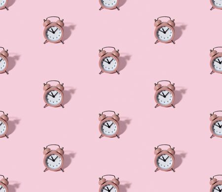Pattern with pink alarm clock on pastel color paper background. Creative morning time minimal style conceptの写真素材