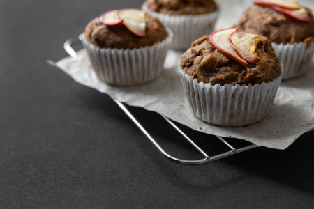 Homemade vegan banana muffins on cooling rack. Vegetarian egg-free bakery on dark background with...