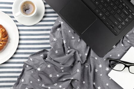 Flat lay top view workspace in cozy bedroom. Laptop, planner and coffee cup in bed. Work from home concept.の写真素材
