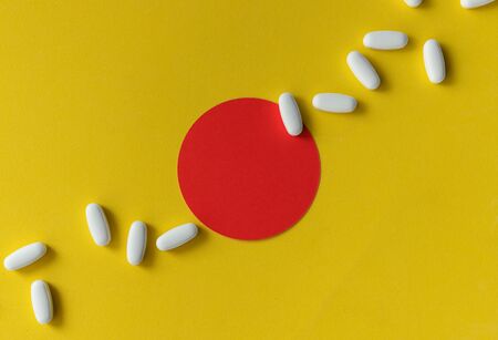 Creative composition with white tablets pills on yellow background. Health care treatment conceptの写真素材