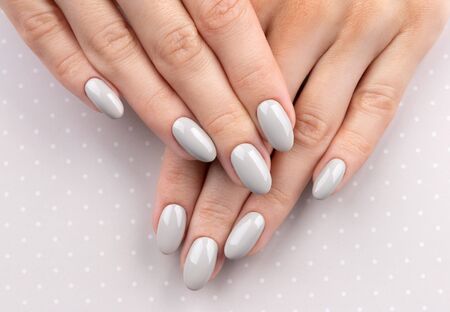 Beautiful womans hands with manicure close up on polka dot background. Gray nail polish. Beauty salon concept. の写真素材