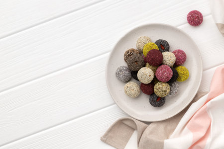 Colorful vegan candies energy balls on a plate on a white wooden table. Flat lay top view healthy...