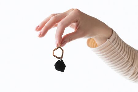 Beautiful young womans hand with nude beige pink manicure holding earring. Beauty salon mock up templateの写真素材