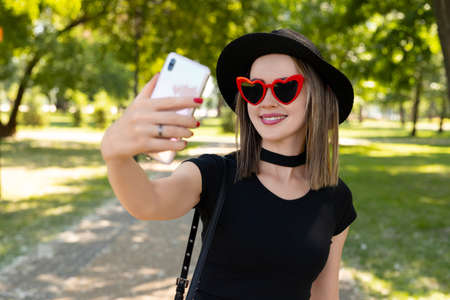 Portrait of beautiful woman makes selfie in the park.の写真素材