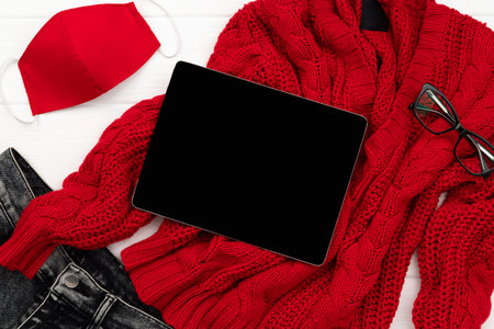 Womens autumn winter clothes look with protective mask on white wooden background. Flat lay top view...
