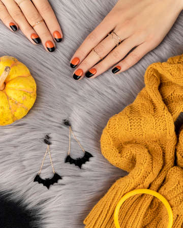 Manicured womans hand with f shion accessories over furry background. Trendy autumn halloween orange nail design.の写真素材