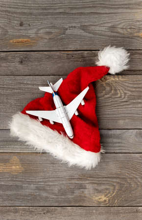 Red Santa hat with toy plane on old wooden backgroundの写真素材