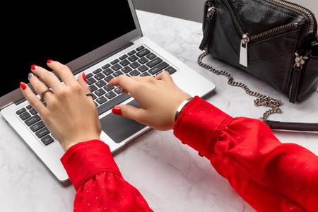 Womans hands with trendy red manicure typing on the keyboard