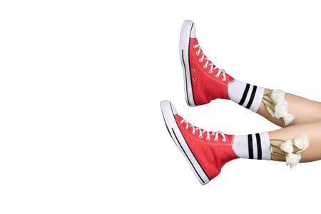Womens legs in stylish red sneakers and white socks with flowers. Footwear shopping sale concept