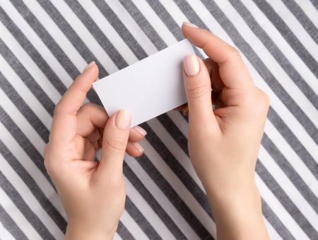 Manicured womans hands holding blank card. Flat lay, top view work at home office education concept.の写真素材