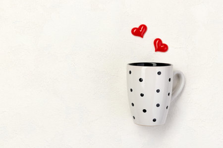 Polka dot white cup with red hearts on white background with copy spaceの写真素材