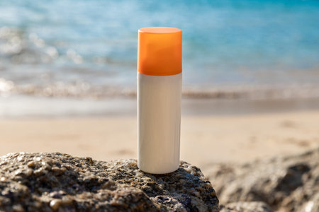Bottle of sunscreen lotion on the beach by the seaの写真素材