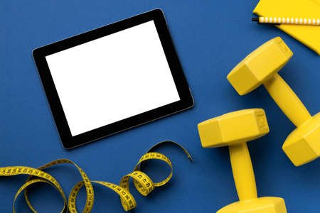 Flat lay top view tablet with yellow sport equipments on classic blue backgroundの写真素材