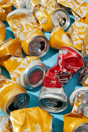 BANGKOK, THAILAND - MARCH 16TH, 2021: rumpled singha lemon soda Coca Cola cans on blue backgroundのeditorial素材