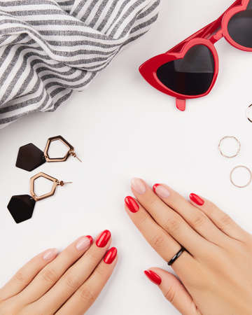 Womans hands with red manicure and fashion accessories on white background. Manicure design trendsの写真素材