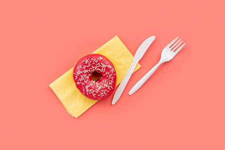 Tasty donut with napkin and cutlery on pink background. Mockup template for bakeryの写真素材