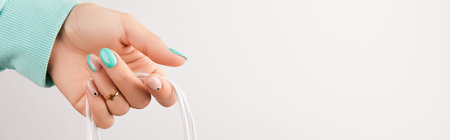 Womans hand holding shopping bag over white background. Turquoise nail design.