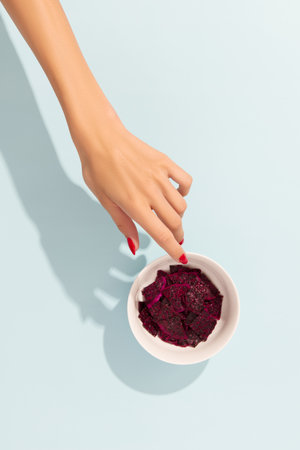 Dried dragon fruit chips and sauce on blue background with womans handの写真素材