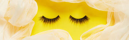 Creative layout with eyelashes. Closed eyes on yellow backgroundの写真素材