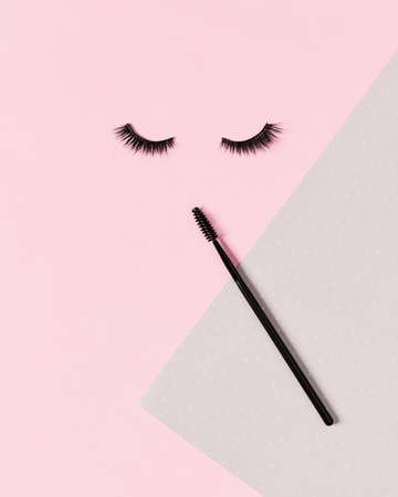 Creative layout with eyelashes and brush mascara. Closed eyes on pastel pink background.の写真素材