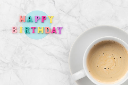 Happy birthday text from wooden colorful letters with cup of coffeeの写真素材