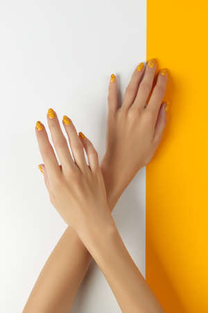 Manicured womans with trendy nail design on orange backgroundの写真素材