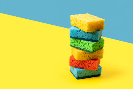 Creative layout with sponges for dishwashing on yellow and blue backgroundの写真素材