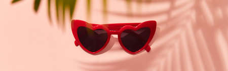 Red heart shaped sunglasses on pink backgroundの写真素材