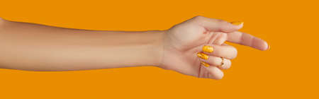 Womans hand with jewelry accessories over orange backgroundの写真素材