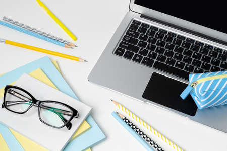 Laptop with blank screen, glasses and stationery on white modern tableの写真素材
