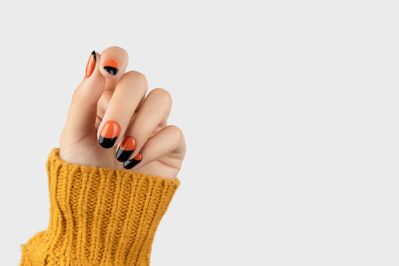 Manicured womans hand on white background. Trendy autumn halloween orange nail designの写真素材