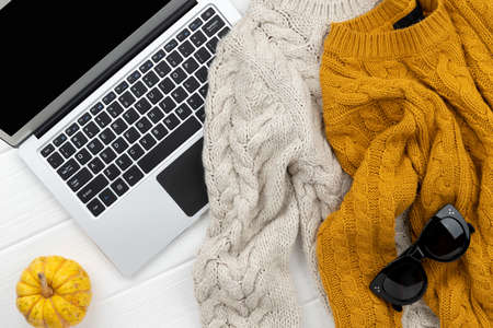 Womens autumn sweaters and laptop on white wooden backgroundの写真素材