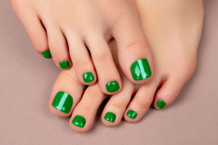 Womans feet with green nail polish on brown backgroundの写真素材