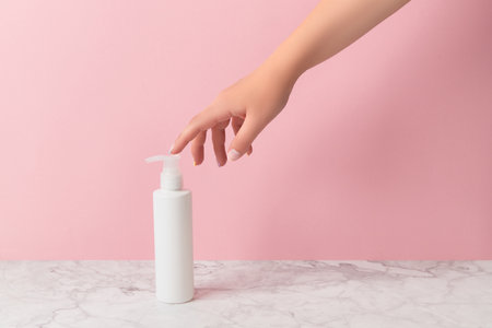 Groomed womans hand touch bottle of lotion or creamの写真素材