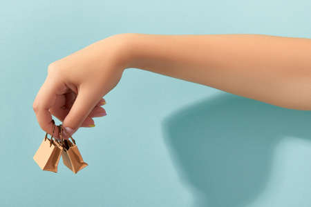 Womans hand with trendy manicure holding tiny paper bags