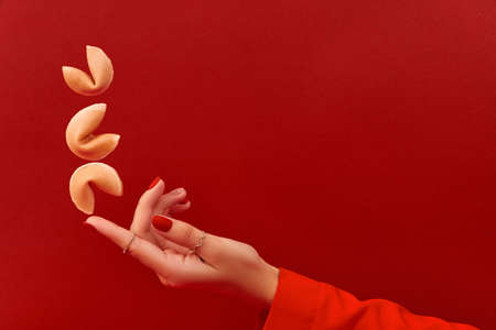 Creative composition with women hand and flying fortune cookie on red backgroundの写真素材