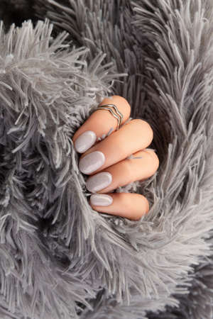 Manicured womans hand holding furry gray fabricの写真素材