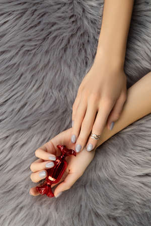 Womans hands holding ornaments on gray furry coverの写真素材