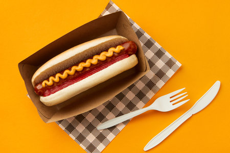 Classic hot dog with wurst, ketchup and mustard on orange background. Restaurant menu delivery tacke away conceptの写真素材