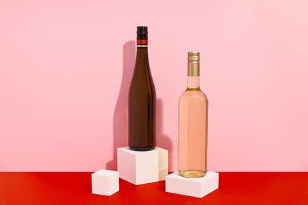 Bottles of wine on red and pink background with deep shadows. Mock up drink with place for you lable and textの写真素材