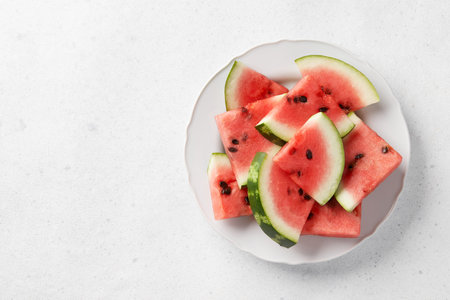 Watermelon slices with seeds on gray background. Fresh juicy fruit on a plate