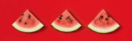 Flat lay top view watermelon in sunlight. Sliced fruit on red backgroundの写真素材